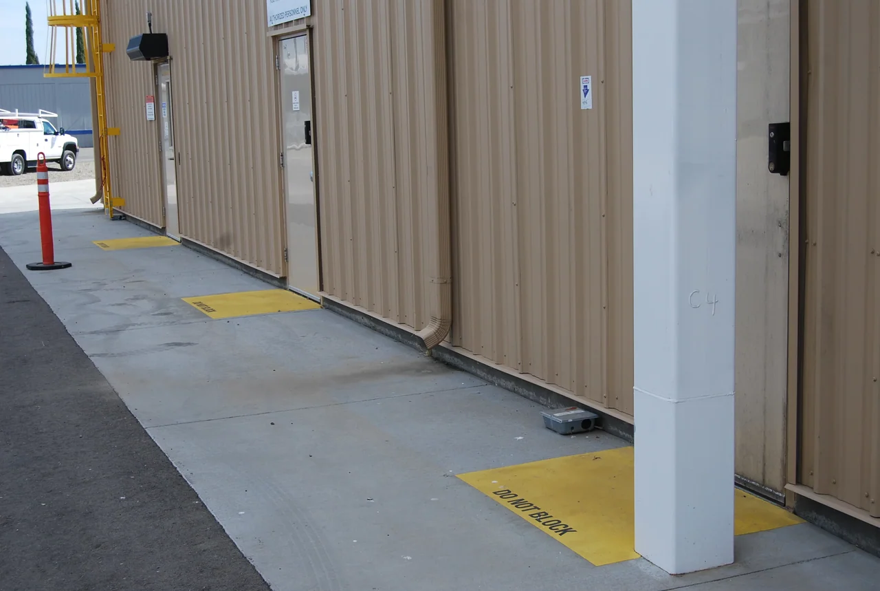 Metal building walkway with yellow do-not-block safety striping by Gold Star Painting