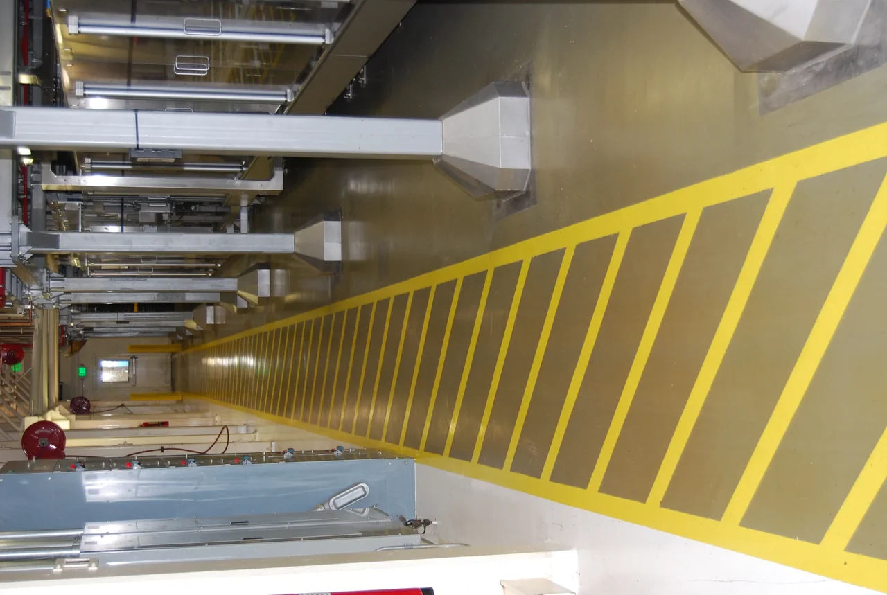 Yellow safety striping along a plant walkway by Gold Star Painting